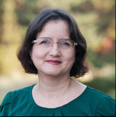 Photo of author Cynthia Capley standing in front of a garden at Kensington Palace in London.
